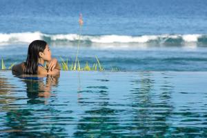 a woman laying in the water in the ocean at Jeeva Klui Resort in Senggigi