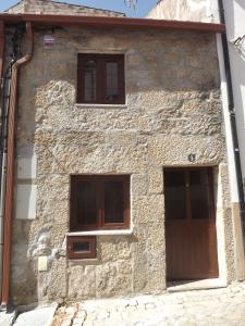 a stone building with three windows and a wooden door at Casa dos Poetas in Belmonte