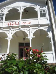 a white building with a wall rose sign on it at Pension Waldrose in Ostseebad Sellin
