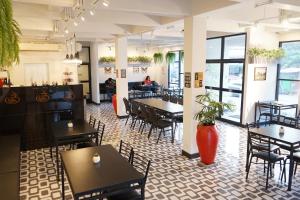a restaurant with tables and chairs and a person in the background at Sabai Place Donmueang Airport in Bangkok