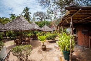 a patio with tables and chairs and straw umbrellas at Capricorn Beach Cottages in Pangani