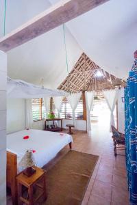 1 dormitorio con 1 cama blanca en una tienda de campaña en Capricorn Beach Cottages en Pangani