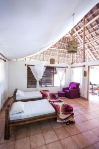 a bedroom with two beds and a living room at Capricorn Beach Cottages in Pangani
