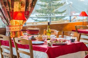a table with a red table cloth and a bottle of wine at Azureva Club La Clusaz les Confins in La Clusaz