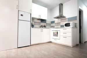 a kitchen with white cabinets and a refrigerator at Edificio Arinaga Golden in Arinaga