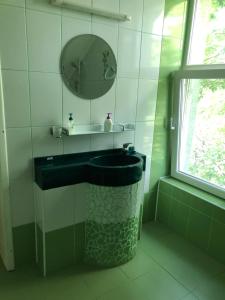 Un baño con un lavabo negro y un espejo. en Casa cu pauni, en Mărăcineni