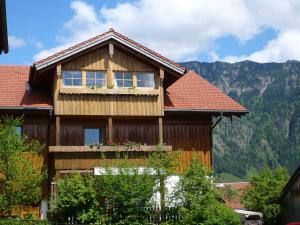 a wooden house with a balcony and mountains in the background at Haus Meinecke in Bad Hindelang
