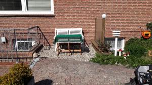 un jardín con un banco verde y blanco frente a un edificio de ladrillo en Haus Möweninsel, en Neue Tiefe Fehmarn