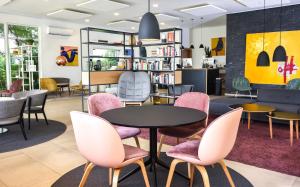a library with pink chairs and a table and bookshelves at Nordic Hotel Abuja in Abuja