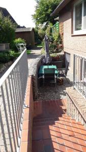 a patio with a table and an umbrella next to a house at Haus Möweninsel in Neue Tiefe Fehmarn