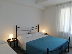 a bedroom with a bed with a blue blanket and two lamps at Akron B&B in SantʼAlessio Siculo