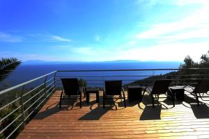 a deck with chairs and a table on top of the ocean at Dio Guesthouses in Leonidio