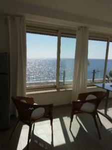 two chairs and a table in a room with windows at Akron B&B in SantʼAlessio Siculo