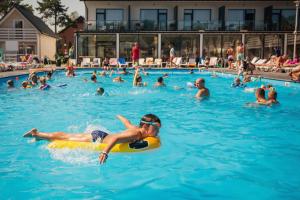 a group of people swimming in a swimming pool at Holiday Park & Resort Grzybowo in Grzybowo