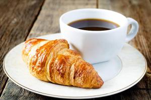 a plate with a cup of coffee and a croissant at Safari Hotel Complex in Samara