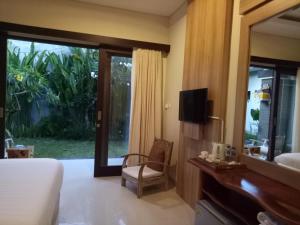 a bedroom with a bed and a tv and a mirror at Guest House Reisya in Nusa Dua