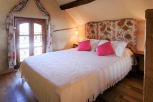 - une chambre avec un grand lit blanc et des oreillers roses dans l'établissement Domaine La Carrière, à Toulon-sur-Allier