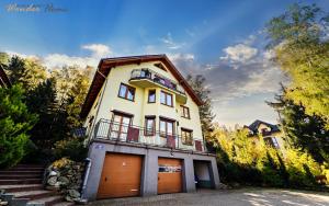 a white house with two garage doors and stairs at Wonder Home - Apartamenty z balkonami przy szlakach turystycznych - blisko plac zabaw i boisko do gry in Karpacz