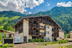 un edificio de apartamentos con montañas en el fondo en Base Camp: Residence Ferme de Montenvers, en Chamonix-Mont-Blanc