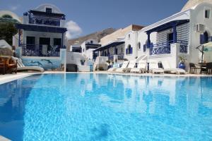 a swimming pool with blue water in front of white buildings at Samson΄s Village in Perissa