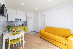 un soggiorno con divano giallo e tavolo di Madimà a Sorrento