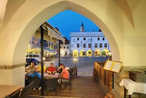 un grupo de personas sentadas en una mesa en un arco en Hotel Zlaty Andel, en Český Krumlov