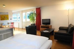 um quarto de hotel com uma cama e uma televisão e cadeiras em SEEGER Living Comfort Downtown em Karlsruhe