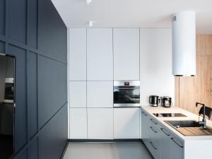 uma cozinha com armários brancos e um frigorífico preto em Ataner Apartamenty em Koszalin