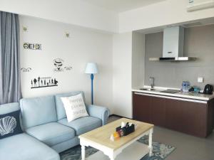Il comprend un salon avec un canapé bleu et une cuisine. dans l'établissement 惠东巽寮湾无敌海景公寓, à Huidong