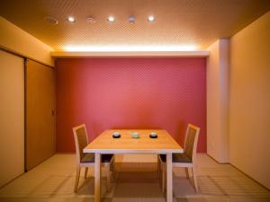 a dining room with a wooden table and chairs at Dogo Onsen Yachiyo 道後温泉八千代 in Matsuyama