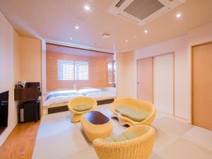 a bedroom with a bed and wicker chairs at Dogo Onsen Yachiyo 道後温泉八千代 in Matsuyama