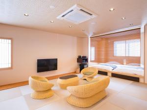 a living room with two chairs and a bed at Dogo Onsen Yachiyo 道後温泉八千代 in Matsuyama