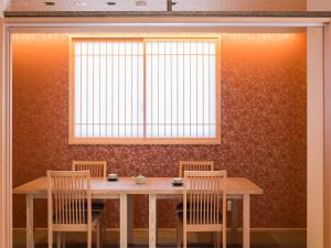 a wooden table with three chairs and a window at Dogo Onsen Yachiyo 道後温泉八千代 in Matsuyama