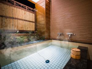 a bathroom with a tub with a barrel in it at Dogo Onsen Yachiyo 道後温泉八千代 in Matsuyama
