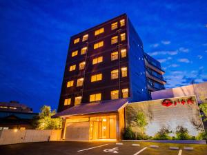 a tall building with lights on in a parking lot at Dogo Onsen Yachiyo 道後温泉八千代 in Matsuyama