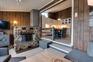 a living room with a stone fireplace and a table at Bitigrenda G in Beitostøl