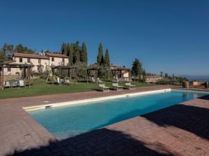 a swimming pool with chairs and a house in the background at Agriturismo La Forra in Cavriglia