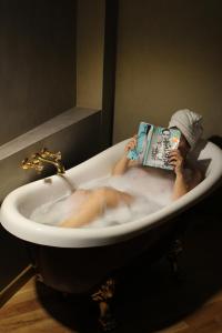 a person sitting in a bath tub reading a book at Appartamenti Trapani In in Trapani