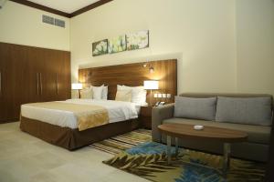 Tulip Al Barsha Hotel Apartment في دبي: غرفه فندقيه بسرير واريكه
