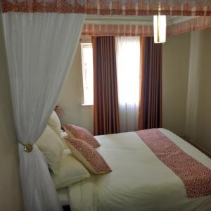 Un dormitorio con una cama blanca con almohadas y una ventana en Adventist LMS Guest House & Conference Centre, en Nairobi