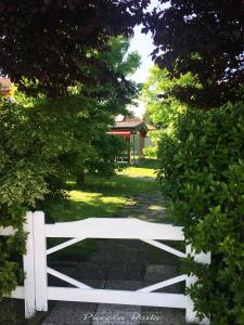einen weißen Zaun in einem Garten mit Bäumen in der Unterkunft piccola baita in Vigevano