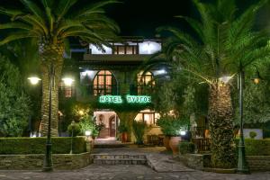 a hotel at night with palm trees in front of it at Pyrgos Hotel in Ouranoupoli