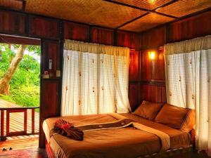 ein Schlafzimmer mit einem Bett in einem Zimmer mit Fenstern in der Unterkunft Phi Phi Green Hill Resort in Ko Phi Phi