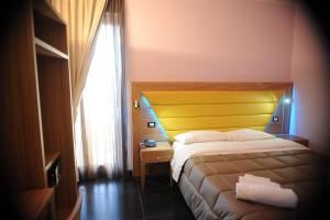 a bedroom with a bed with a yellow headboard and a window at Ostia Antica Suite B&B in Ostia Antica