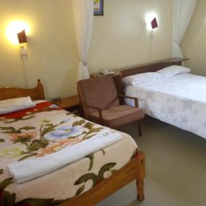 una habitación de hotel con 2 camas y una silla en Adventist LMS Guest House & Conference Centre en Nairobi