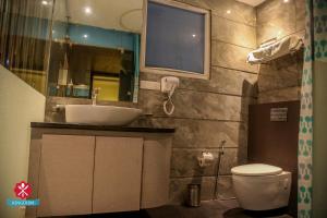 a bathroom with a sink and a toilet and a mirror at Kingdom Hotel in Moga