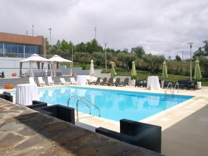 a swimming pool with white tables and chairs next to a building at Hotel Estalagem Turismo in Bragança