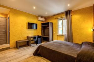 a bedroom with yellow walls and a bed and a television at Hotel Osimar in Rome
