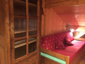 un divano rosso in una cabina di legno con finestra di Le Caribou a Saint-Gervais-les-Bains