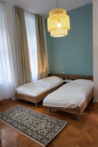 two beds in a room with a chandelier and a rug at #Pobega heritage - self check-in in Timişoara